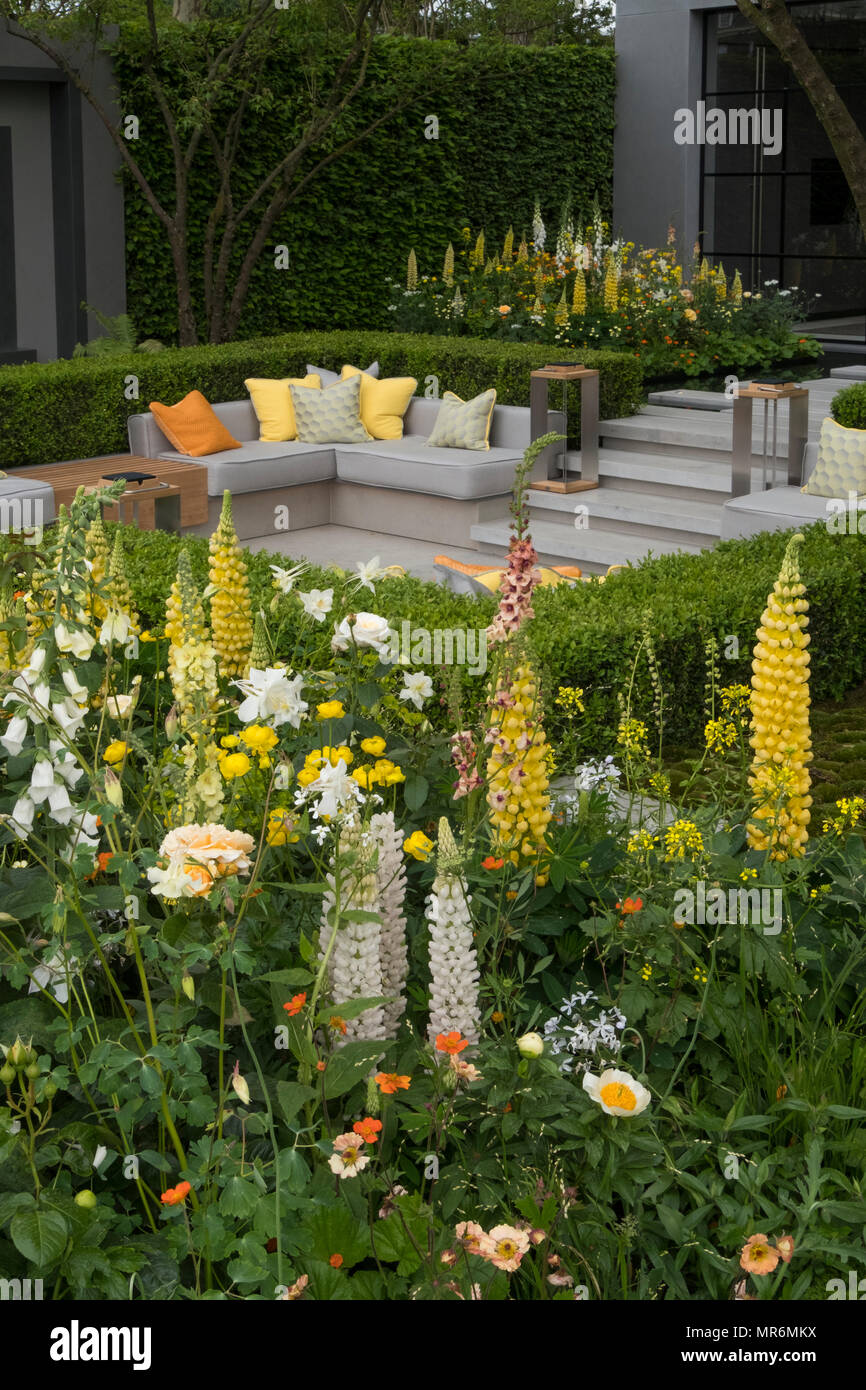 colourful flower garden with outdoor seating in summer Stock Photo