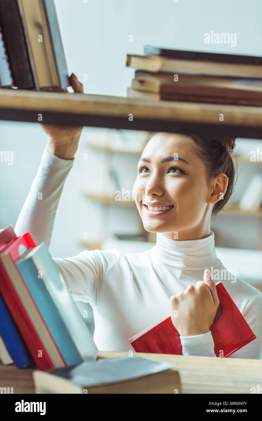 beautiful smiling asian student choosing books in library Stock Photo ...