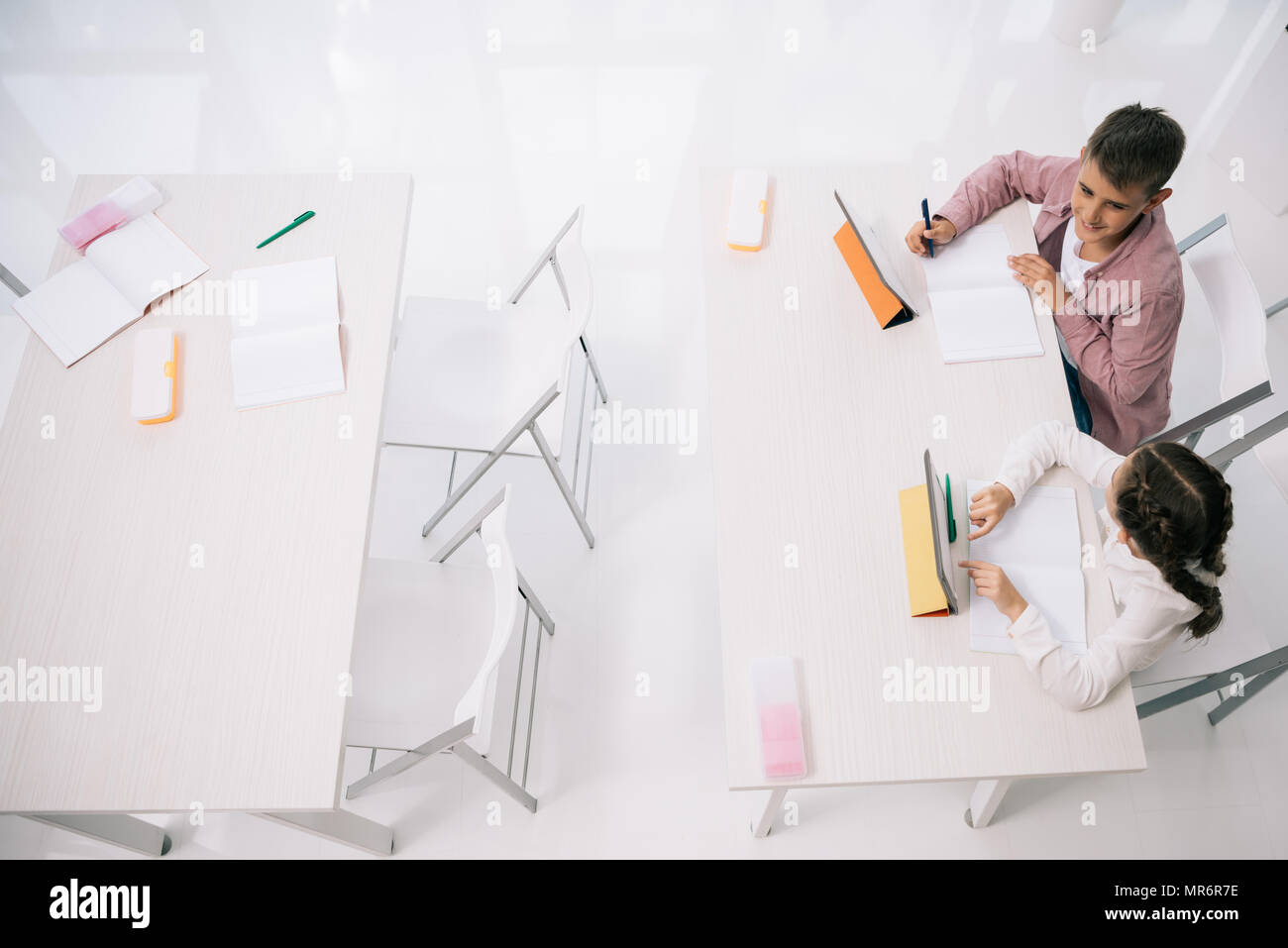 Overhead view of clasmated using digital tablets while sitting at desk in class Stock Photo