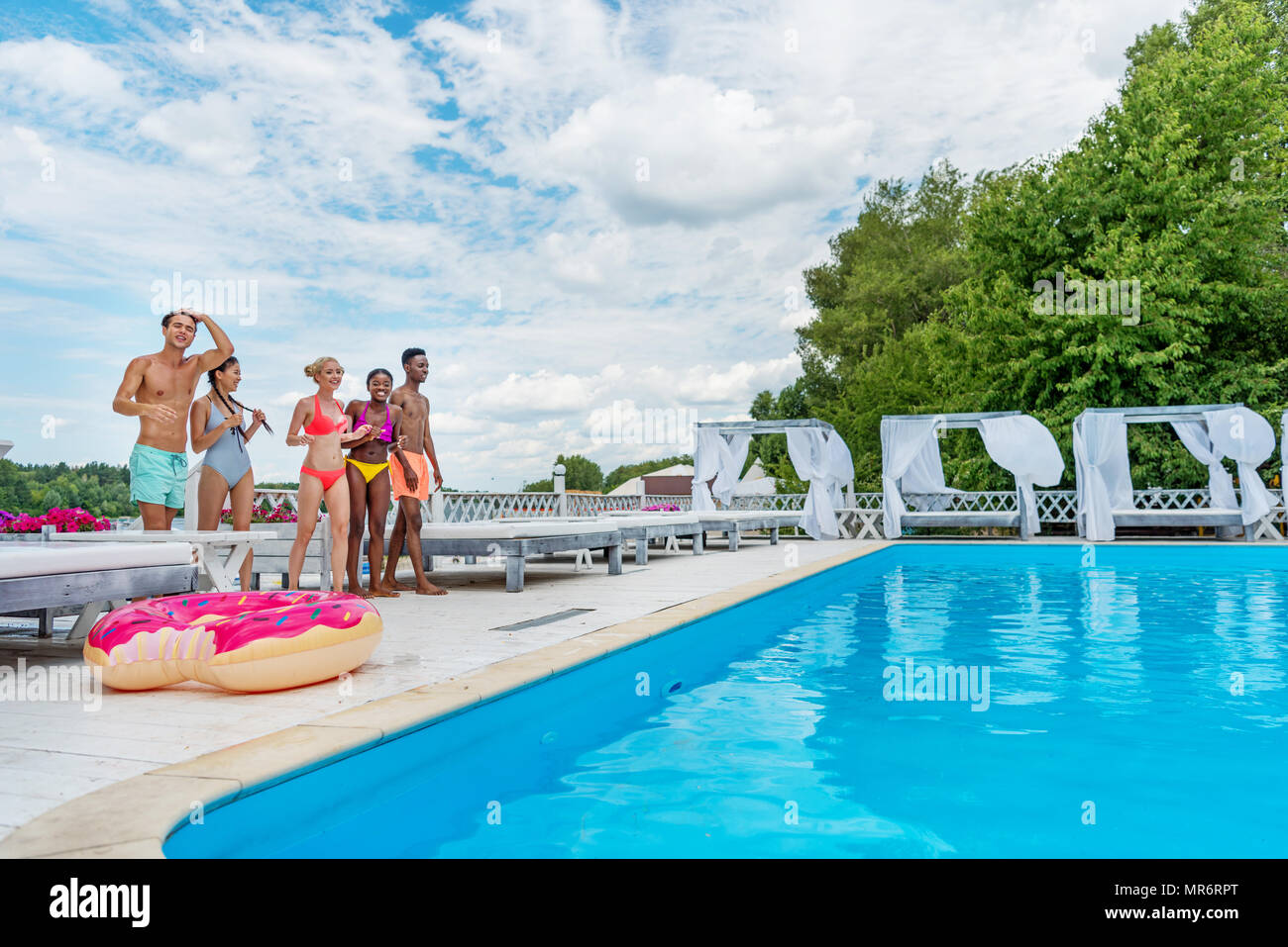 Happy multiethnic friends standing ready to jump into swimming pool ...