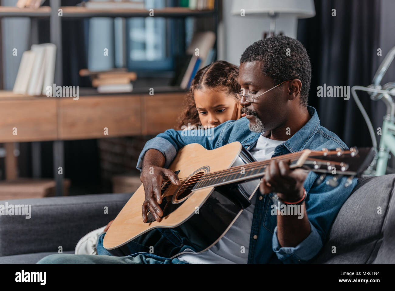 African american man playing guitar with his cute daughter Stock Photo ...