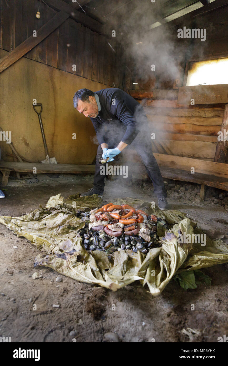 Ancud, Chiloé, Chile: Preparing a traditional Chiloé curanto, in which meats, potatoes and shellfish are cooked in the ground over hot rocks, covered  Stock Photo
