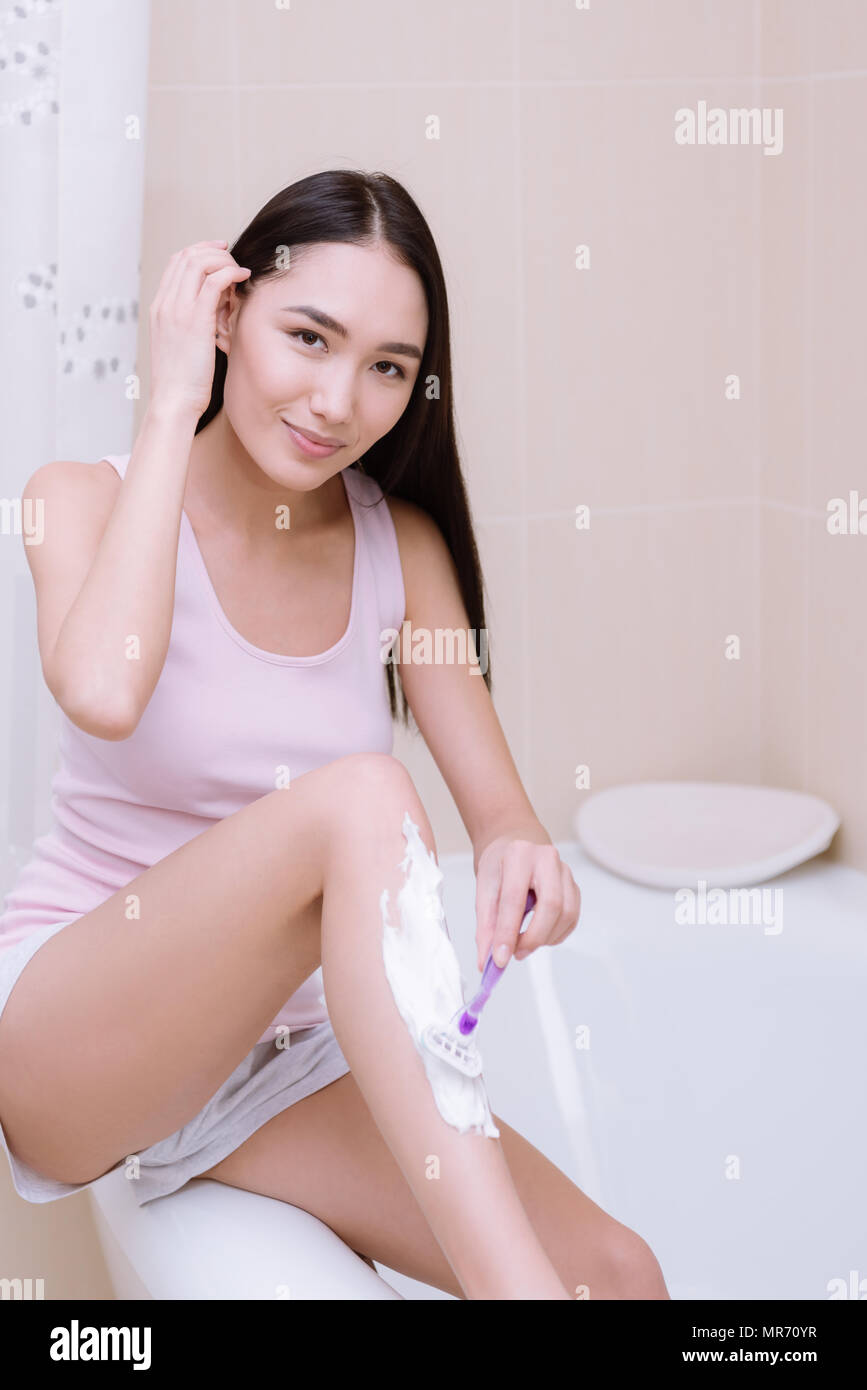 beautiful asian girl shaving leg in bathroom and looking at camera Stock  Photo - Alamy