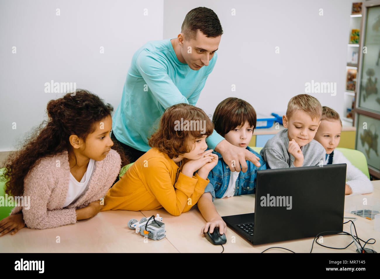 little kids working with teacher on programming class Stock Photo - Alamy