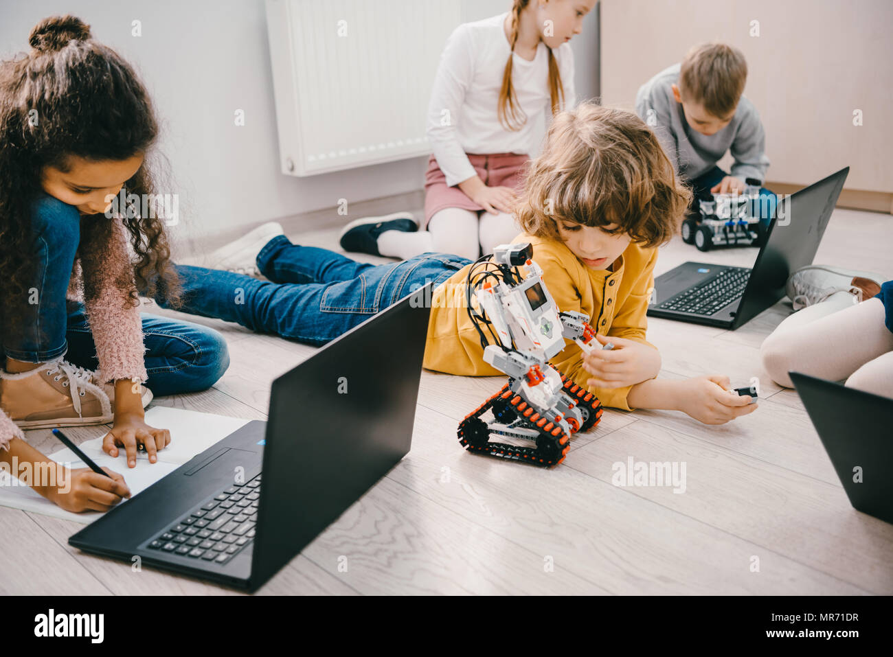 little kids programming with laptops while sitting on floor, stem ...