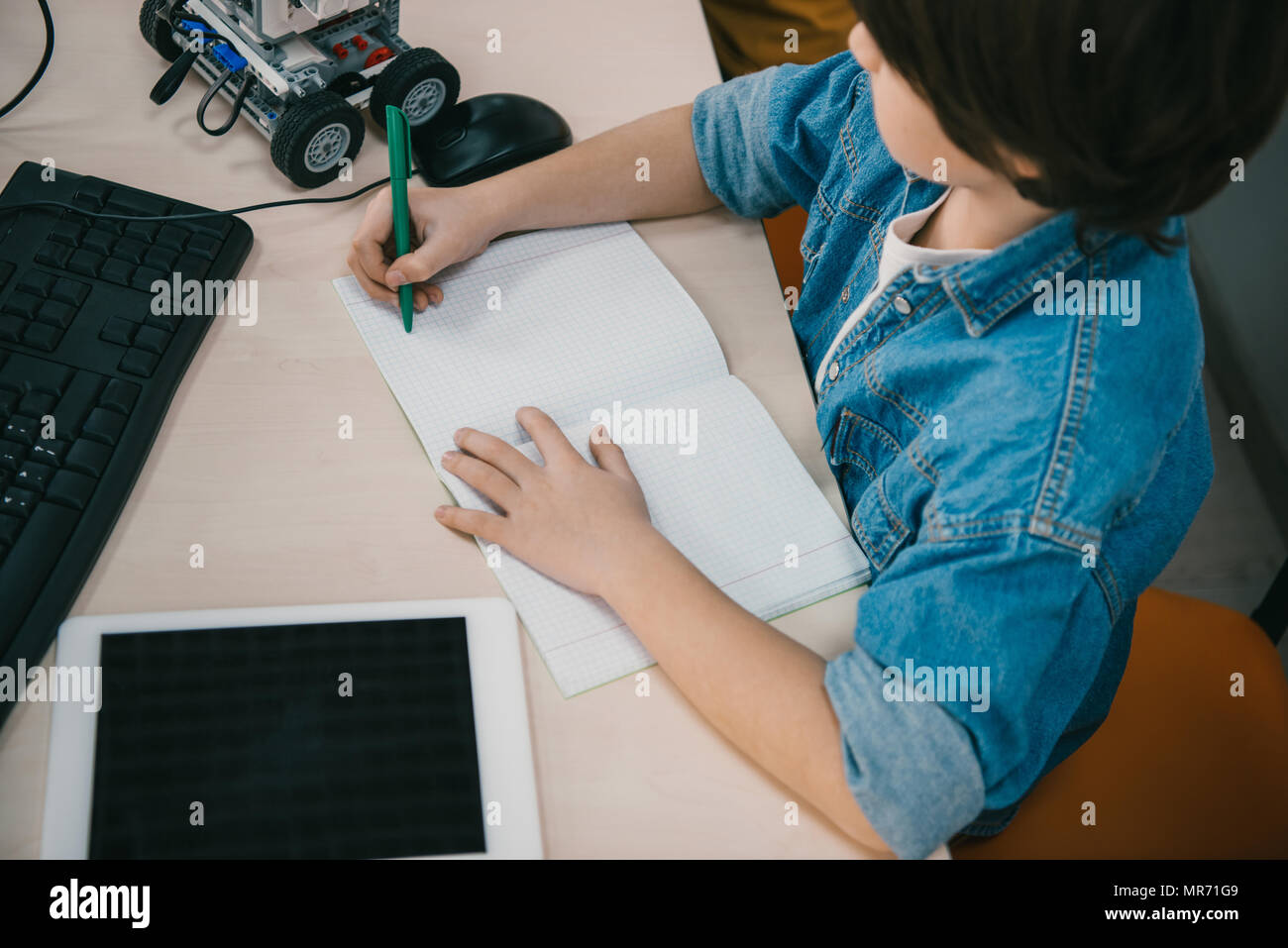 high angle view kid writing in notebook at machinery class Stock Photo