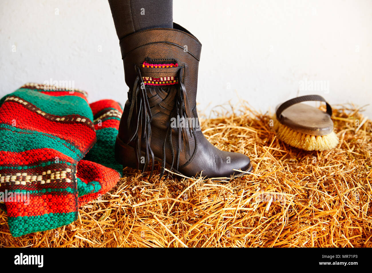 female black boot on stable straw bale with horse brush Stock Photo Alamy
