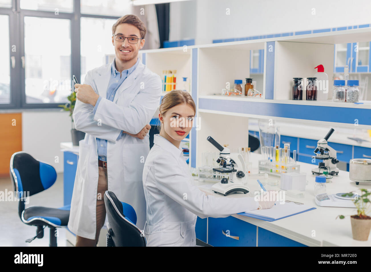 two scientists in white coats working with microscope in laboratory Stock Photo