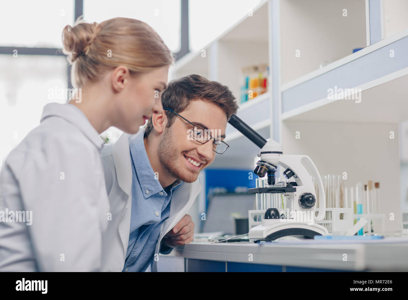 happy scientists in white coats working with microscope in laboratory Stock Photo
