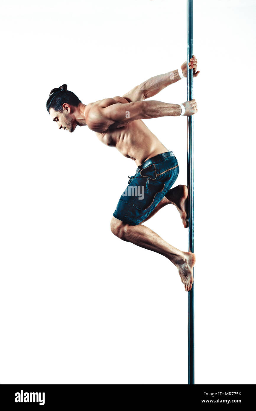 Young strong pole dancing man on white wall background Stock Photo