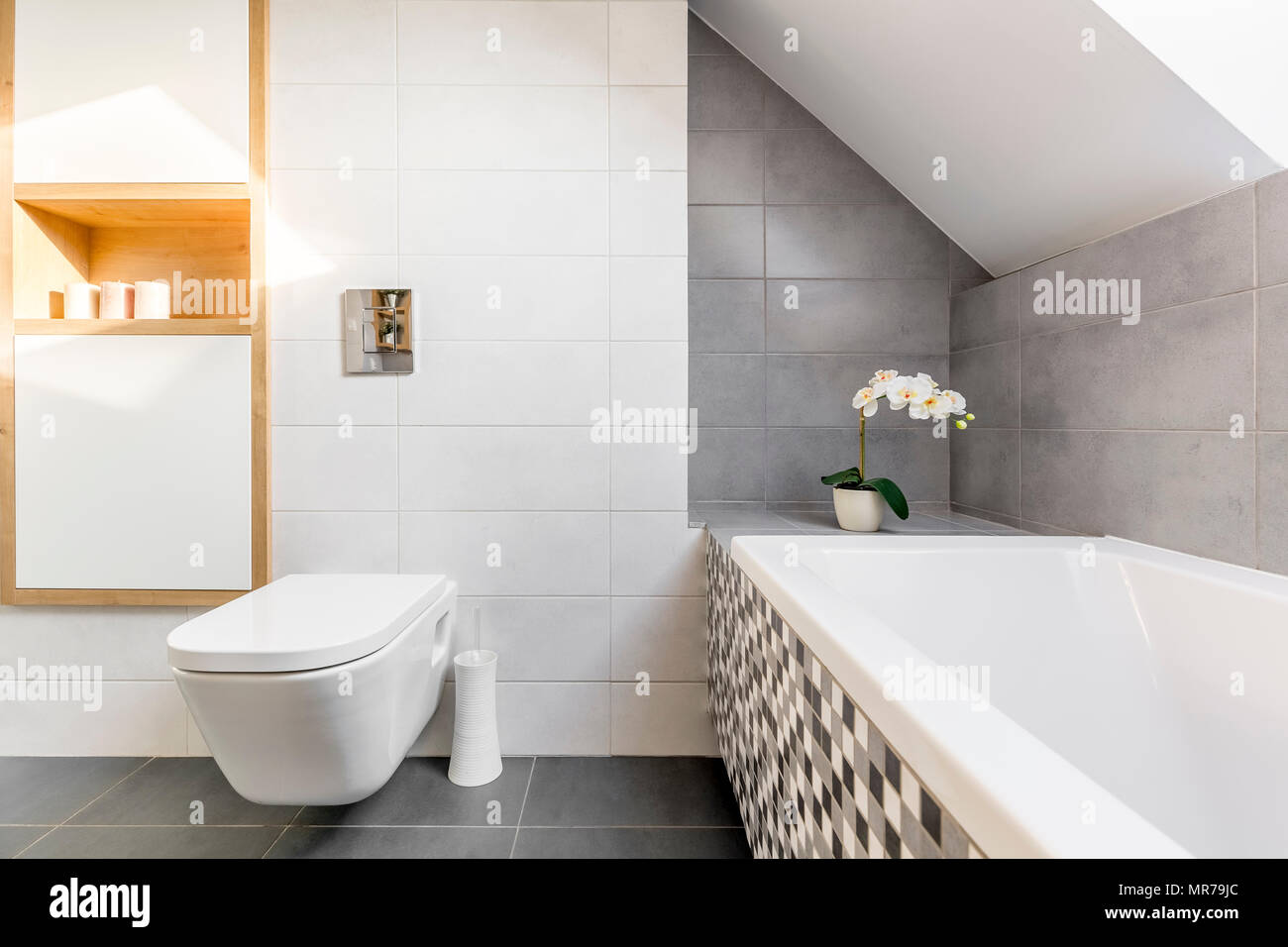 Attic bathroom in grey and white with bathtub and toilet Stock Photo