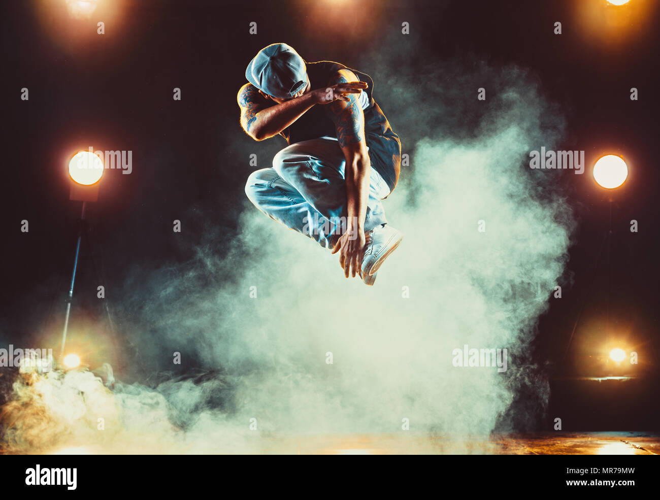 Young man break dancing in club with lights and smoke. Tattoo on body. Stock Photo