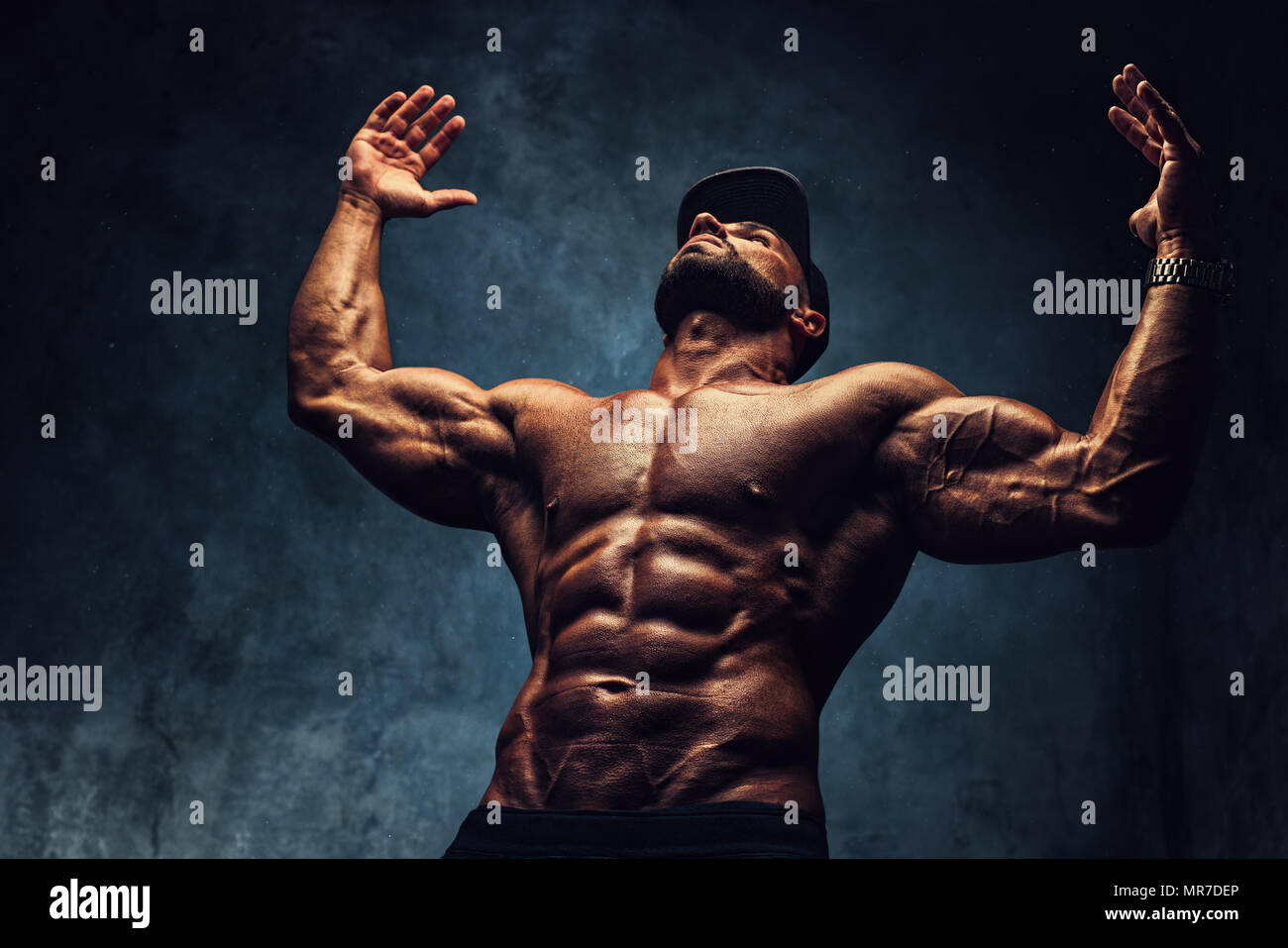 Young strong man bodybuilder in cap on wall background. Dark dramatic  colors Stock Photo - Alamy