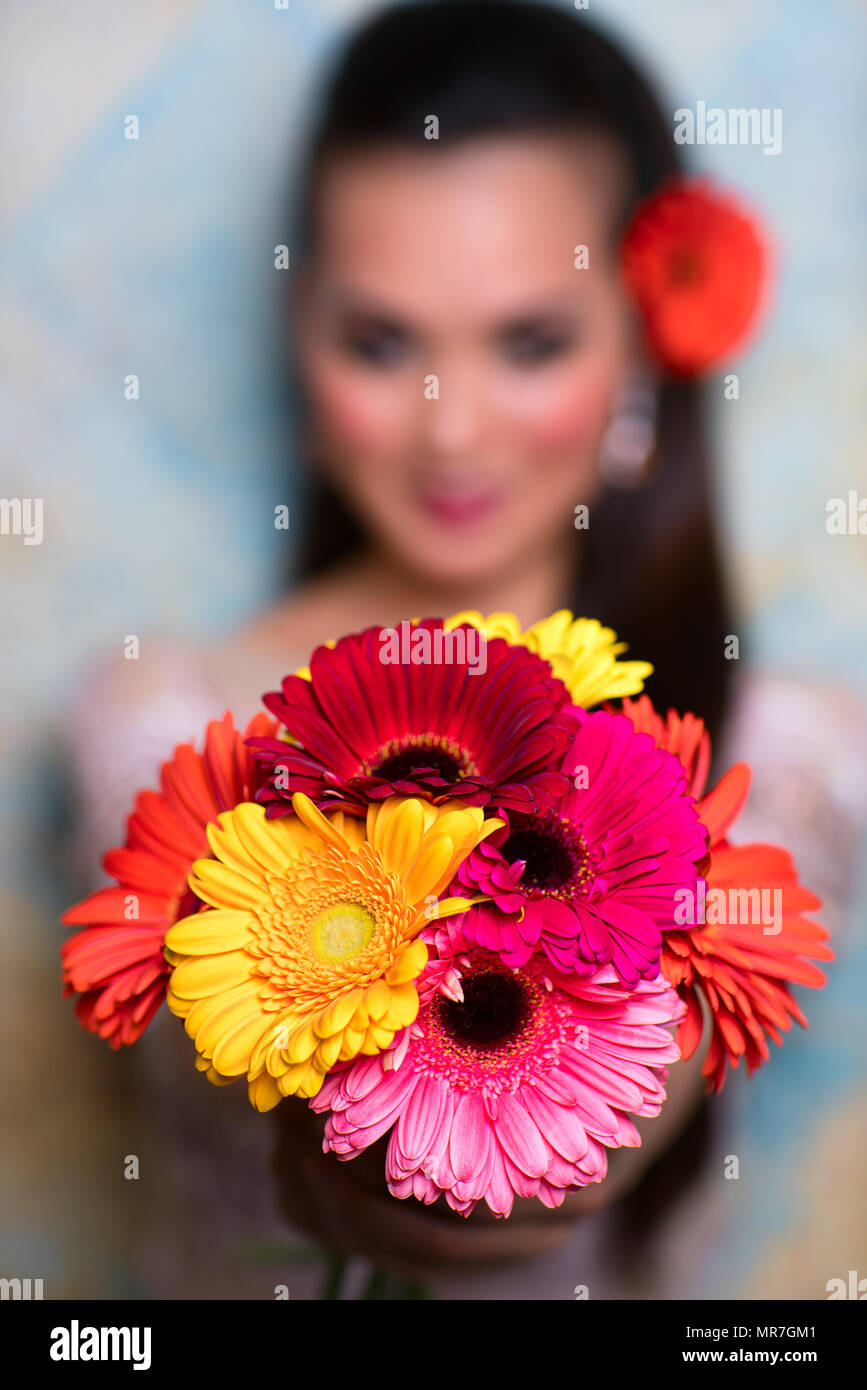Young asian woman holding bouquet of red flowers. Focus on flowers. Stock Photo