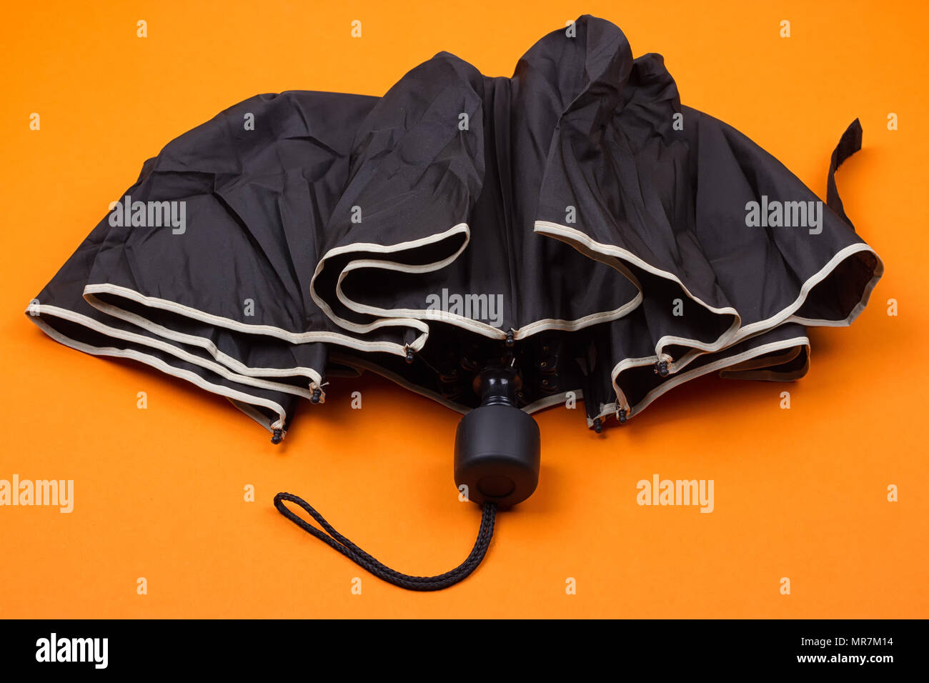closed black umbrella on the orange background Stock Photo Alamy