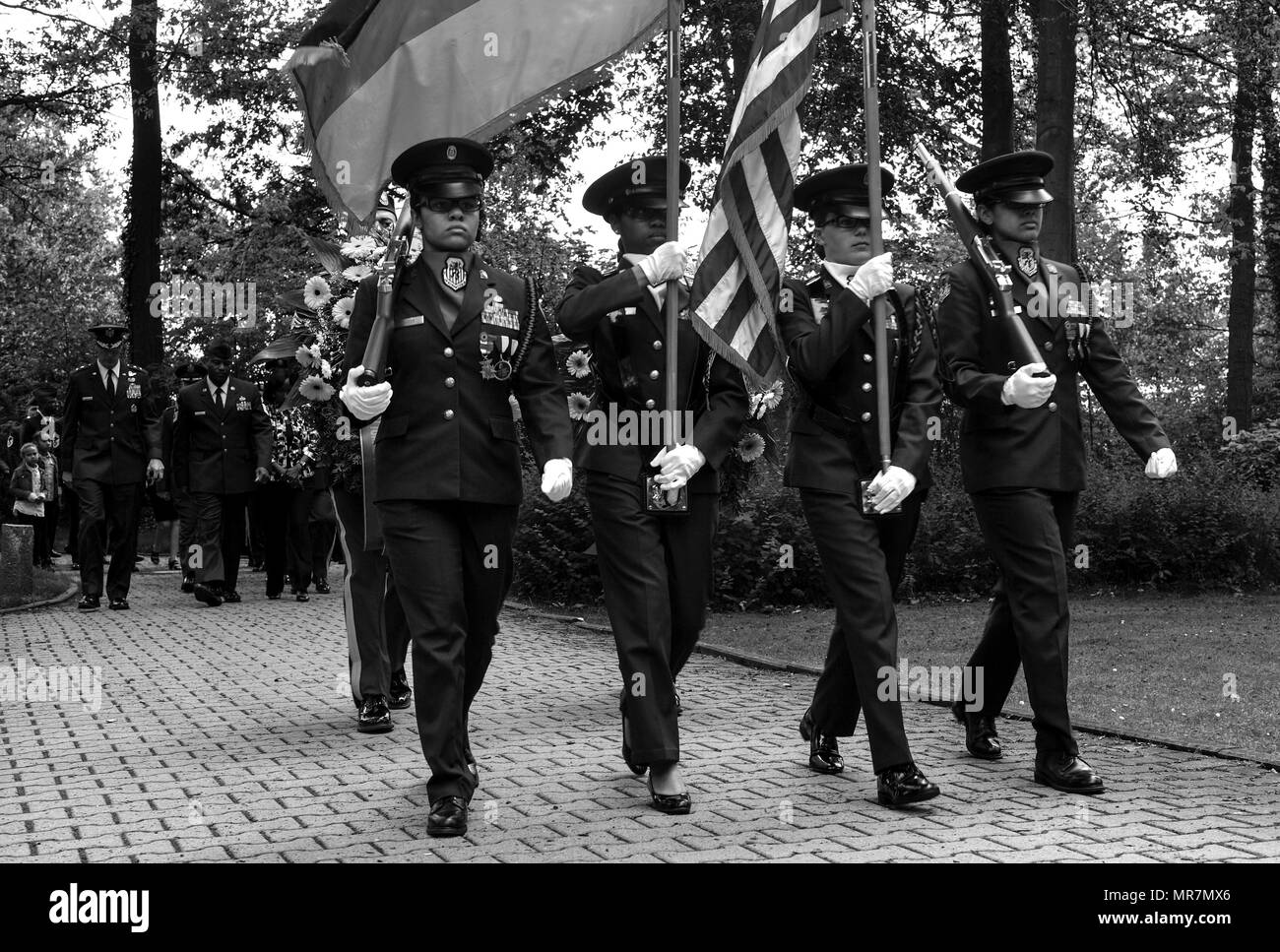 Members of the Ramstein High School Air Force Junior Reserve Officer Training Corps lead a procession of Kaiserslautern Military Community members to the gravesite of 452 American children during the Ramstein Area Chief's Group and German-American and International Women's Club's Kindergraves Memorial Service in Kaiserslautern, Germany, May 20, 2017. The ceremony is held annually to honor the children who were lost from 1952 to 1971. The memorial ceremony included an invocation, laying wreaths, candle lighting, and a blessing of the graves. (U.S. Air Force photo by Senior Airman Tryphena Mayhu Stock Photo