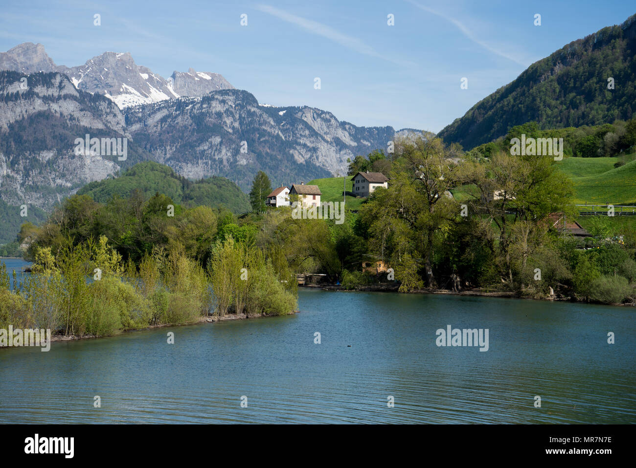 Swiss village on ice cold Walensee lake with mountains in background Stock Photo