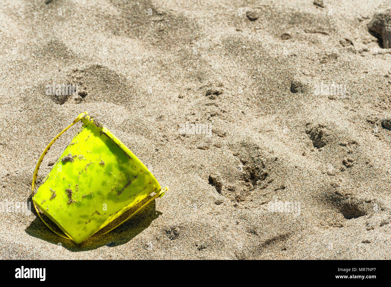 Closeup of a yellow bucket used in playing on a sandy coastal beach. Stock Photo