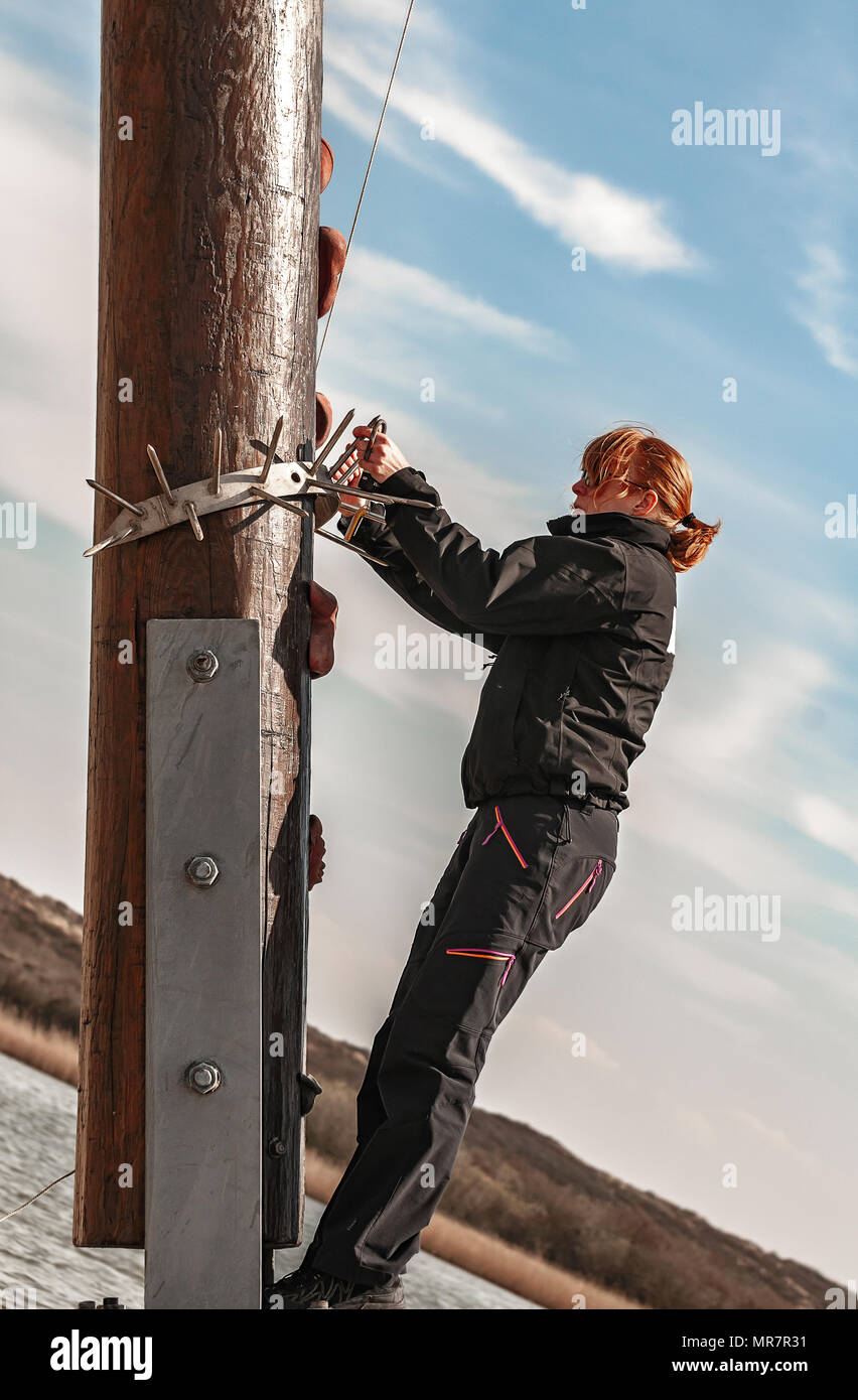 a young woman climbs up on a thick wooden pole Stock Photo
