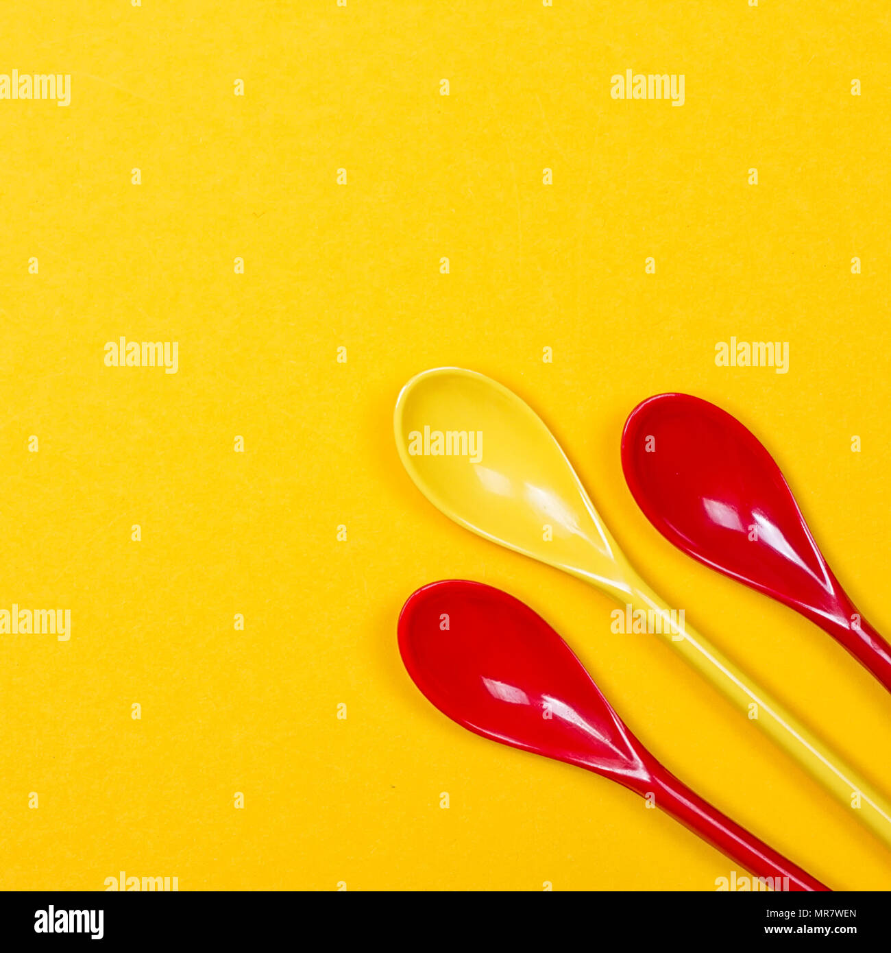 Set of multi-colored long spoons on a yellow background Stock Photo