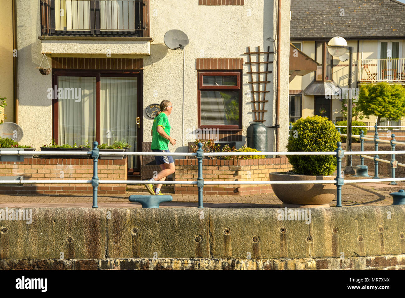 Person jogging on the harbour wall around new homes in the Penarth Marina Stock Photo