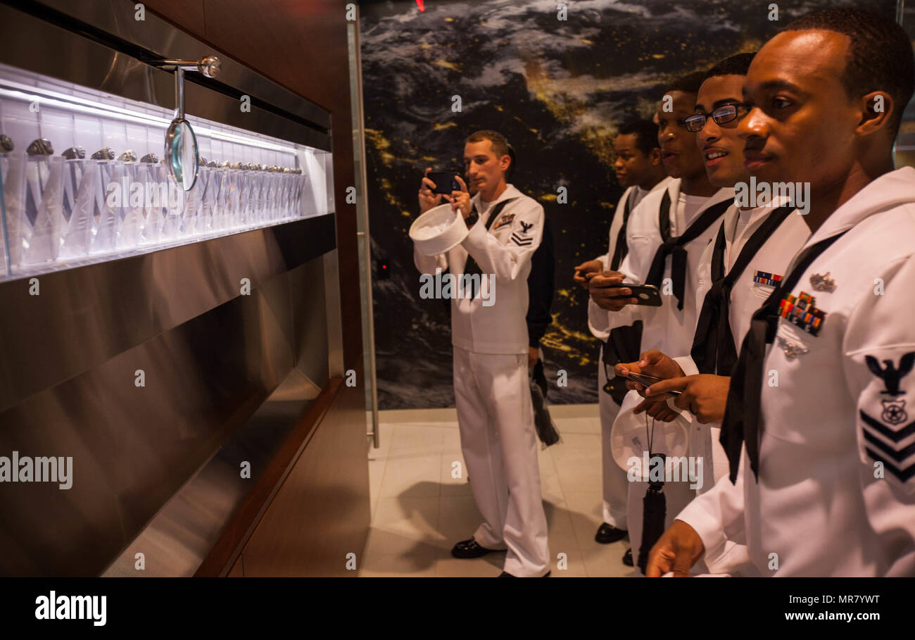 Sailors gather around the display of Super Bowl rings to take in