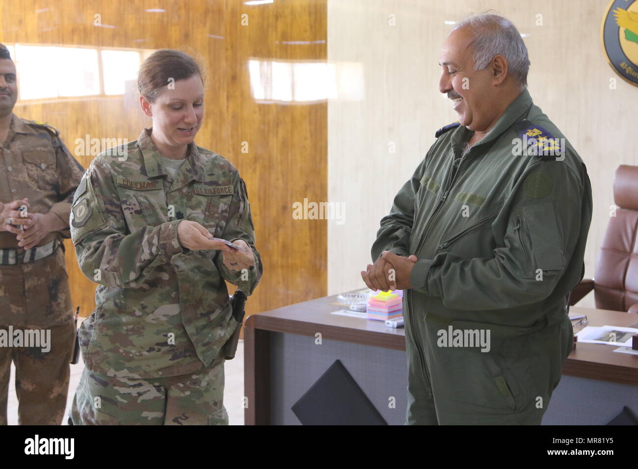 U.S. Air Force Lt. Col. Carolyn Coleman, deployed in support of Combined Joint Task Force-Operation Inherent Resolve, shows her Iraqi air force counterpart a coin during a key leader engagement at Qayyarah West Airfield, Iraq, May 19, 2017. Coleman, the commander of a detachment of the 370th Air Expeditionary Group, enables the Iraqi air force through advising and assisting with air mobility operations. CJTF-OIR is the global Coalition to defeat ISIS in Iraq and Syria. (U.S. Army photo by Staff Sgt. Heidi McClintock) Stock Photo