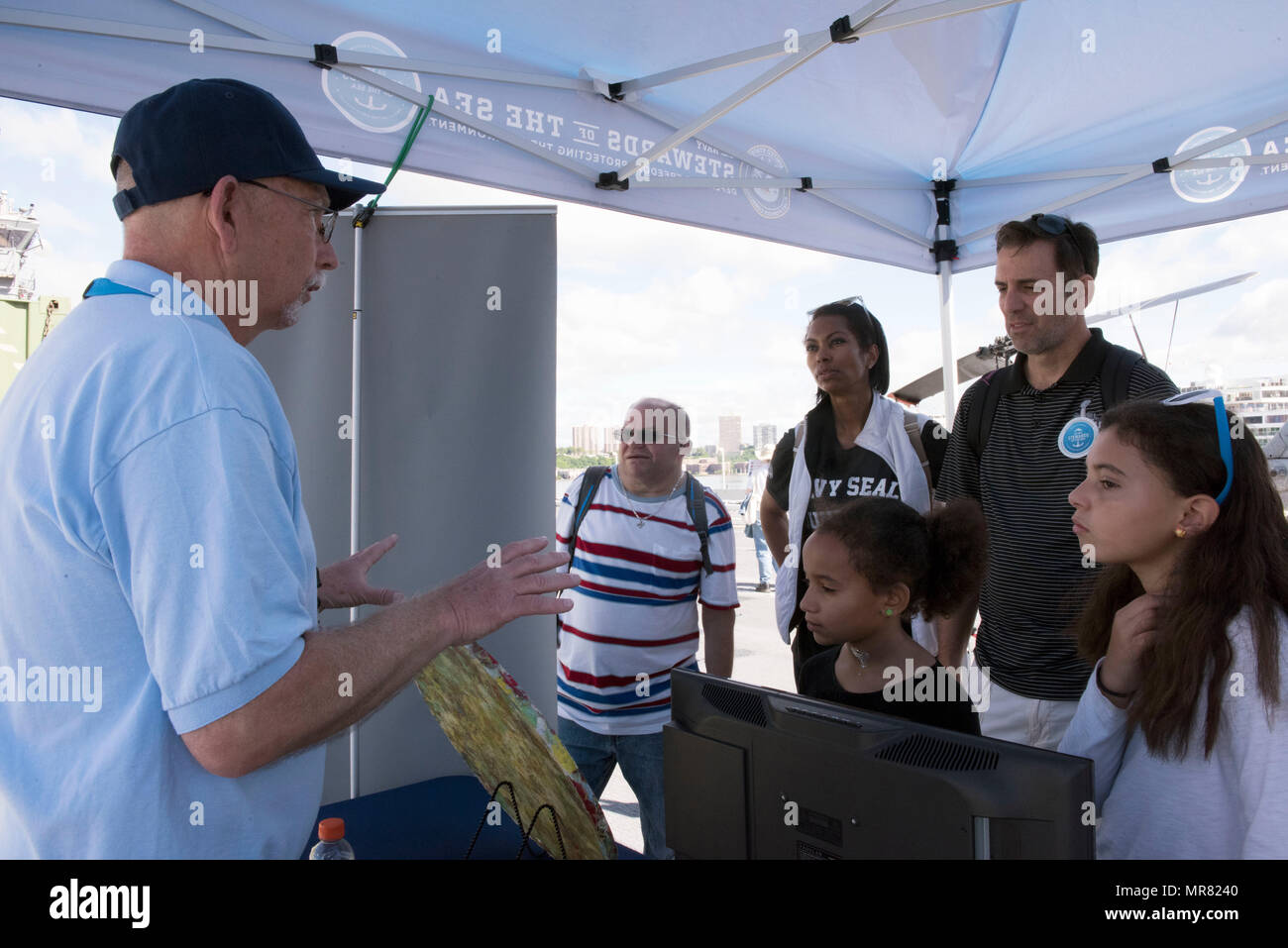 170527-N-MS174-002 NEW YORK (May 27, 2017) Ted Brown, left, an environmental public affairs officer with U.S. Fleet Forces Command, discusses shipboard plastic waste processing with Fox News host Harris Faulkner and her family at the U.S. Navy’s “Stewards of the Sea: Defending Freedom, Protecting the Environment” exhibit aboard the amphibious assault ship USS Kearsarge (LHD 3) during Fleet Week New York.  The Navy employs every means available to mitigate the potential environmental effects of our activities without jeopardizing the safety of our Sailors or impacting our Navy readiness mission Stock Photo