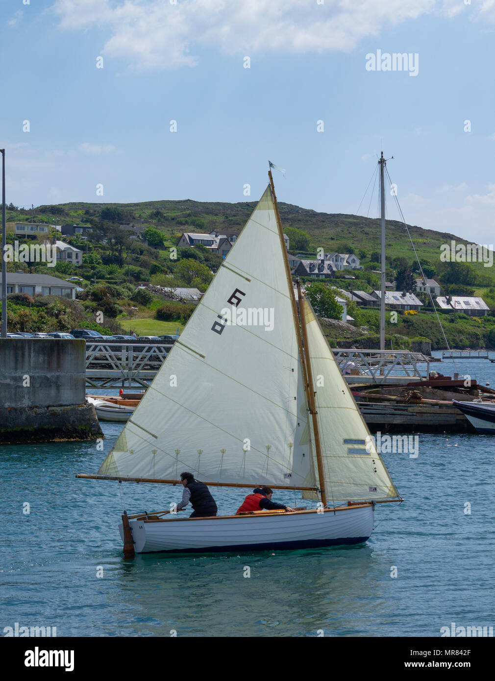clinker built wooden sailing dinghy or boat being sailed in Baltimore harbour, Ireland by a couple enjoying the summer weather. Stock Photo