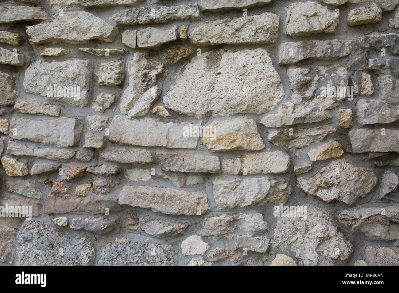 Old wall made of big stones and broken bricks. Vintage rough blocks surface background Stock