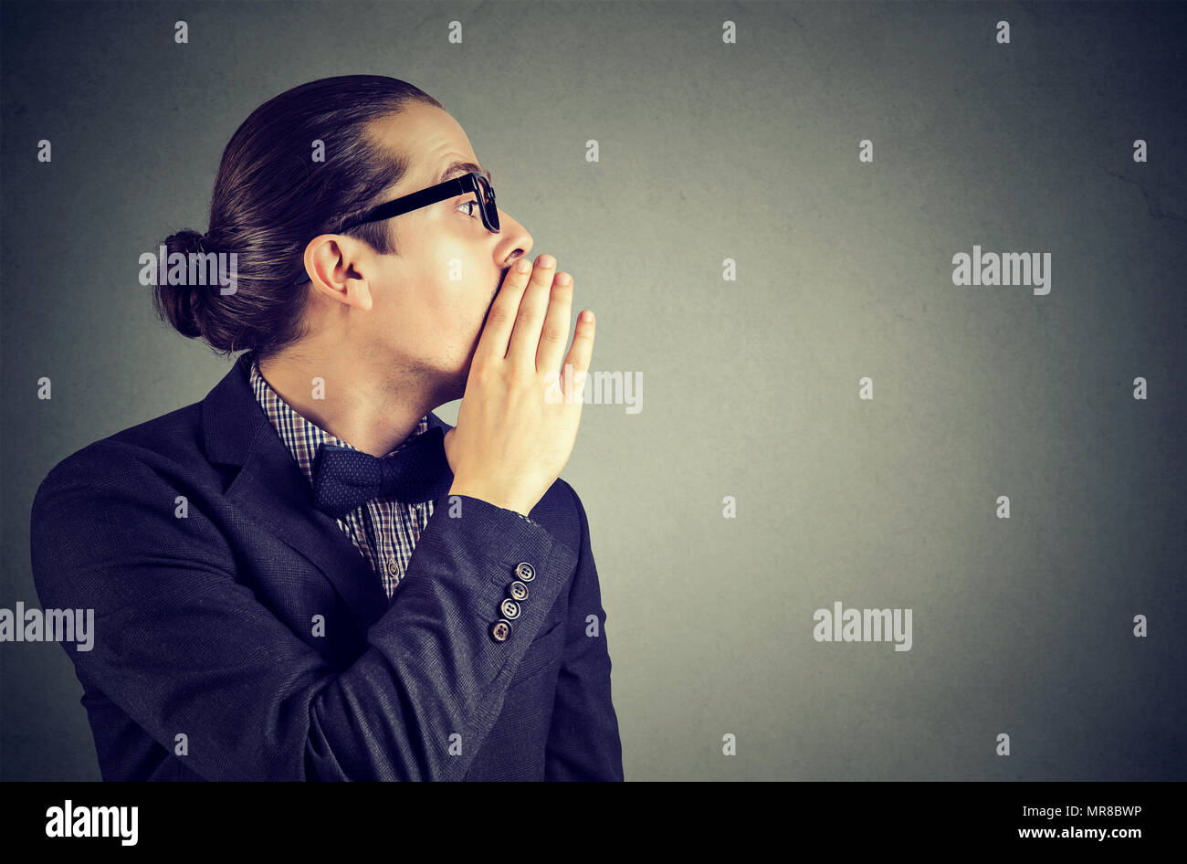 Young man covering mouth while gossiping and telling secrets in whisper. Stock Photo