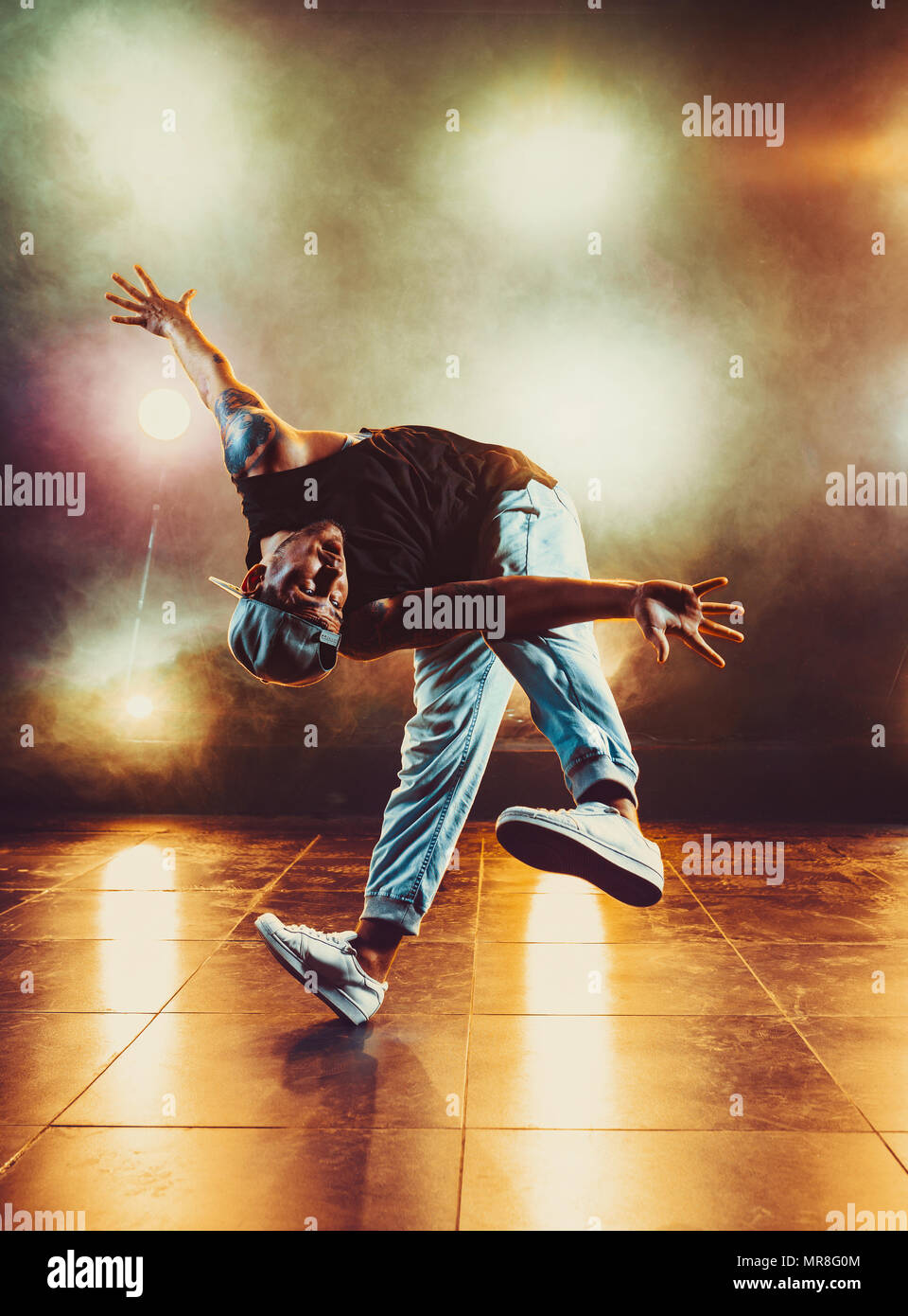 Young man break dancing in club with lights and smoke. Tattoo on body. Stock Photo
