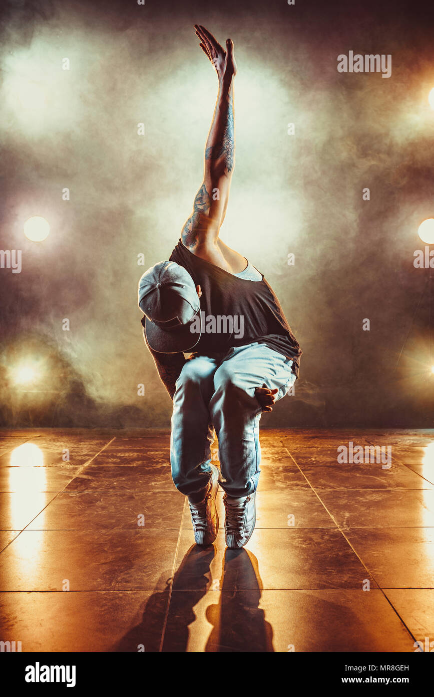 Young cool man break dancing in club with lights and smoke. Tattoo on body. Stock Photo