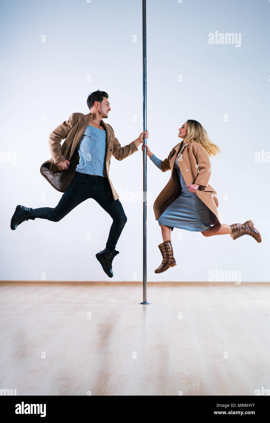Young man and woman pole dancers in casual autumn clothing jumping Stock Photo
