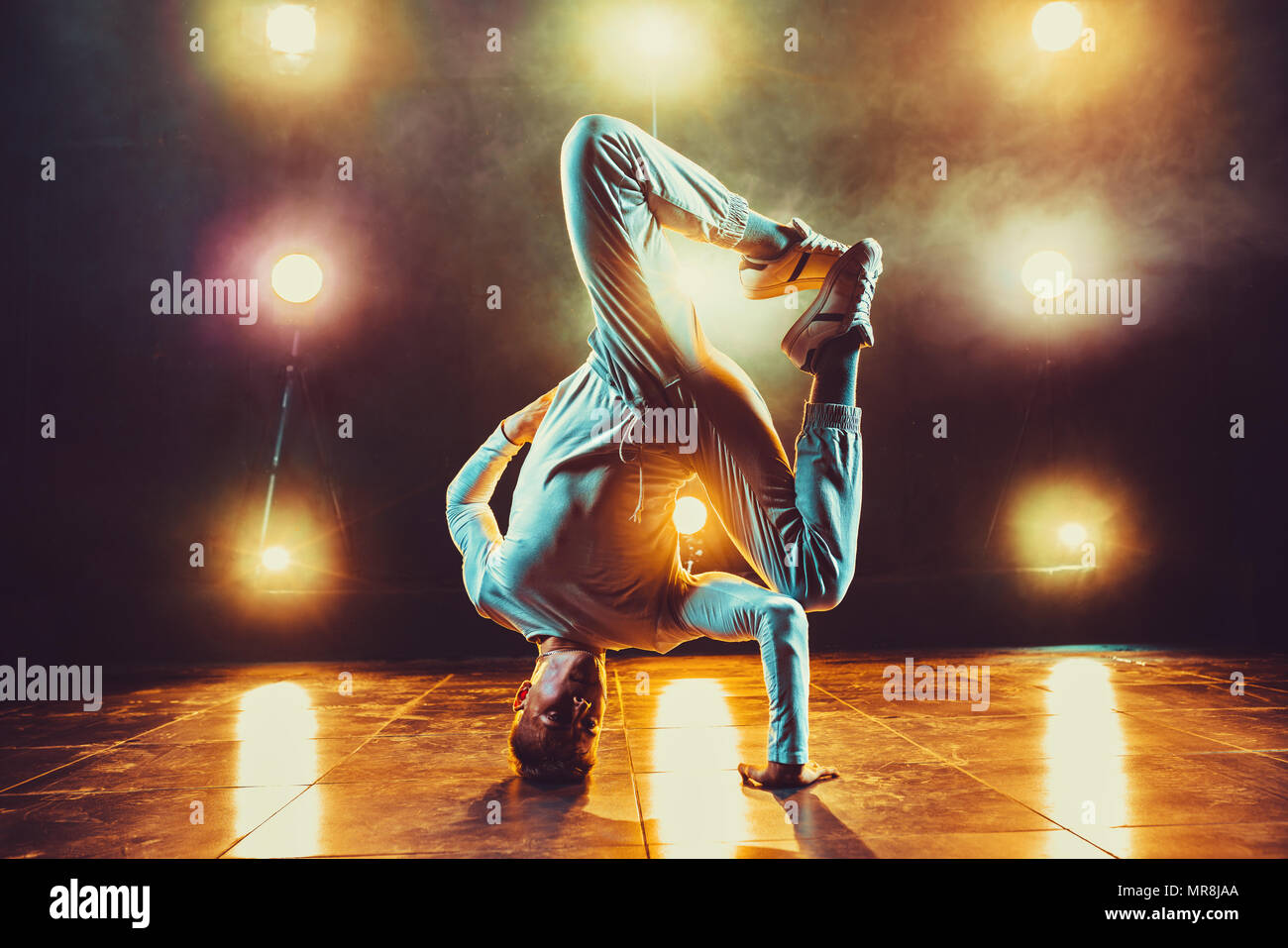 Young man break dancing in club with lights and smoke. Warm colors. Stock Photo