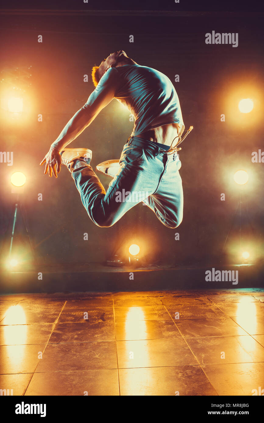Young man break dancing in club with lights and smoke. Warm colors. Stock Photo