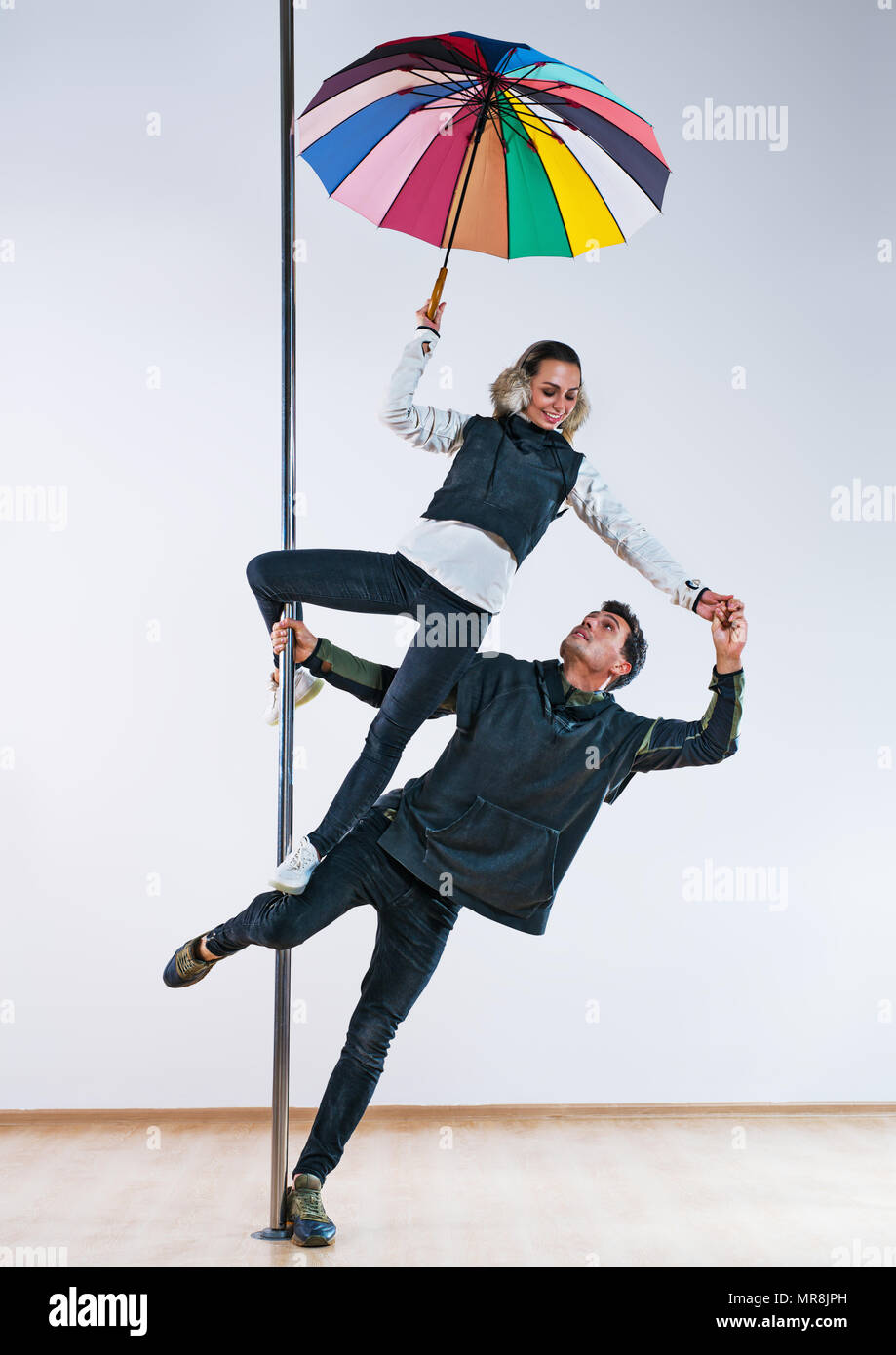 Young man and woman pole dancers in casual autumn clothing with umbrella Stock Photo