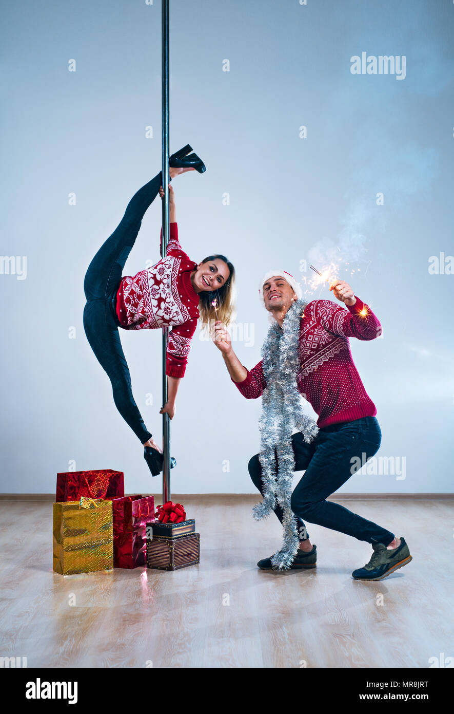 Young man and woman pole dancers in winter new year clothing celebrating Stock Photo