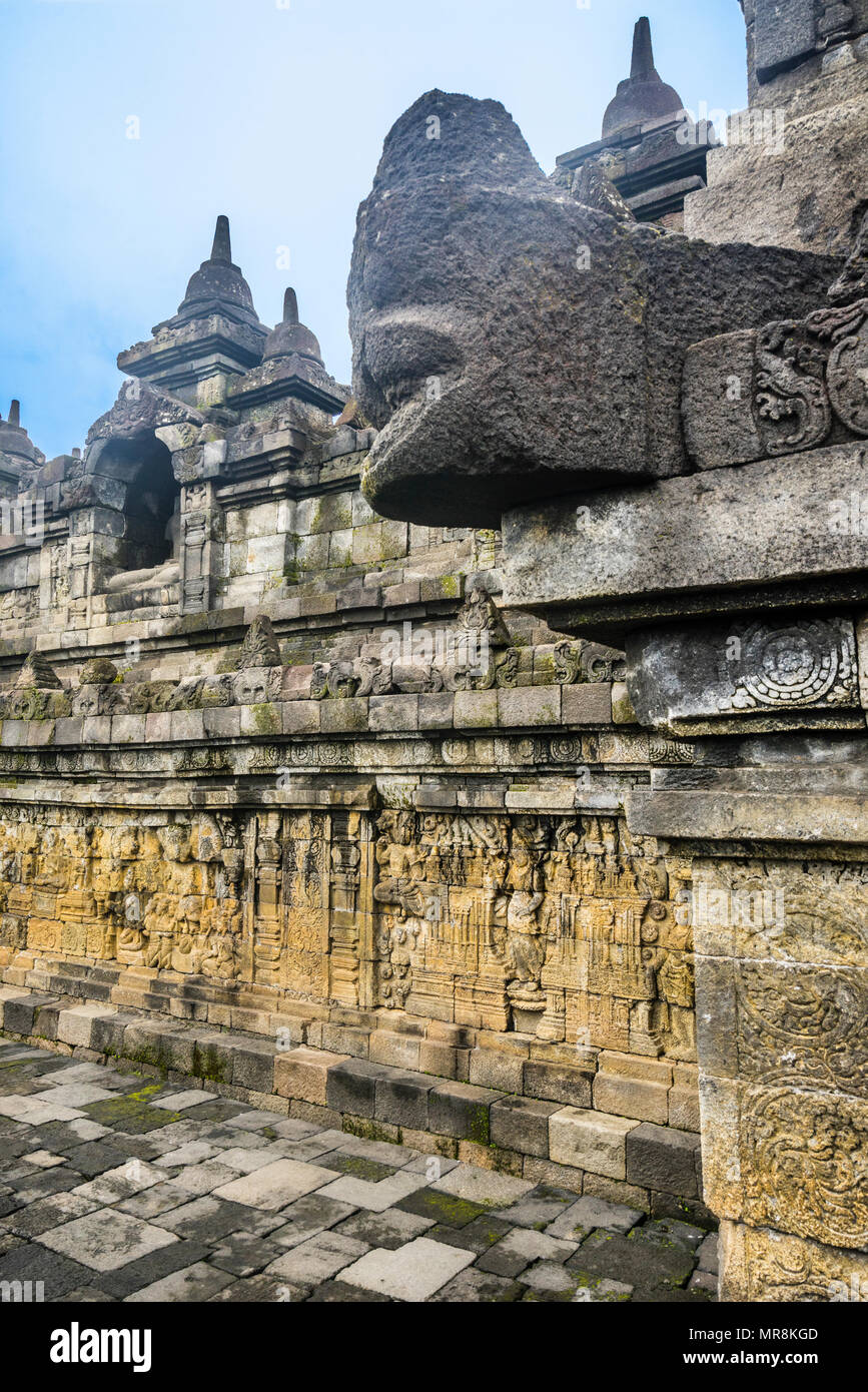 a makara gargoyle protruding over galleries of bas relief panels narrating the Buddhist cosmology at 9th century Borobudur temple, Central Java, Indon Stock Photo