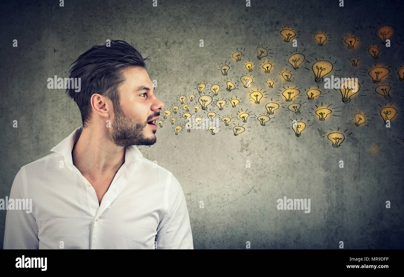 Erudite young man talking spreading smart ideas with light bulbs coming out of his open mouth Stock Photo