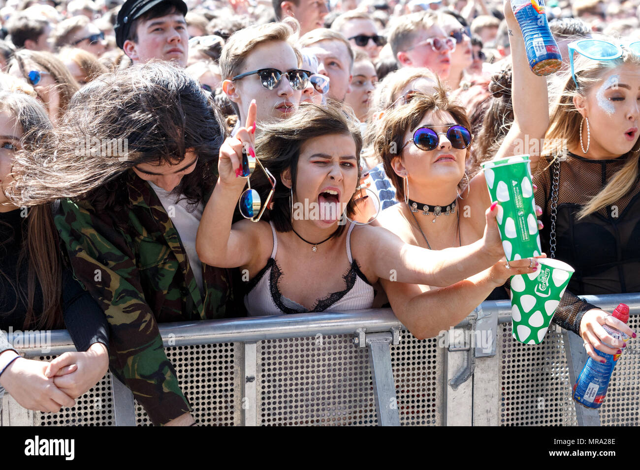 A rocker girl posing for the camera, with her tongue sticking out, in the front row at a music festival. Stock Photo