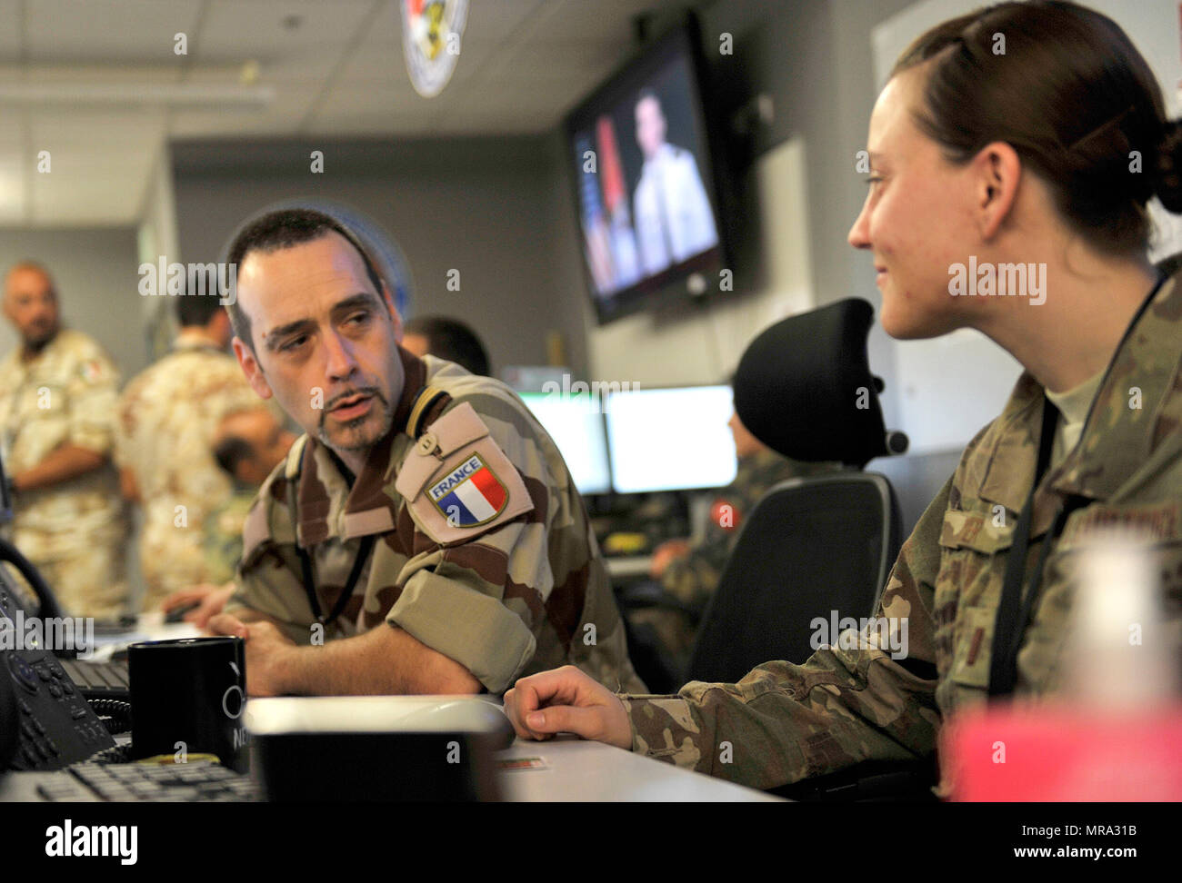 A member of the French air force speaks with a U.S. Airman in the Combined Air Operation Center May 27, 2017, at Al Udeid Air Base, Qatar. The Coalition Forces in the CAOC are responsible for command and control of air power within the Central Command area of responsibility. (U.S. Air Force photo by Staff Sgt. Desiree Economides) Stock Photo