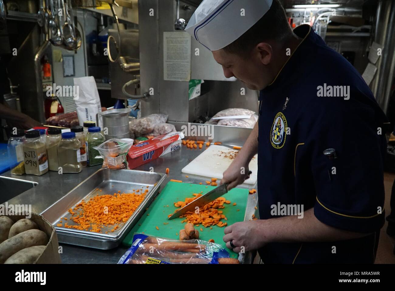 170525-N-QX001-002  ATLANTIC OCEAN (May 29, 2017) Culinary Specialist 2nd Class Drew Iverson, from Nacogdoches, Texas,  dices carrots while preparing lunch for the crew  of the Arleigh Burke-class guided-missile destroyer USS James E. Williams (DDG 95) May 29, 2017. James E. Williams, homeported in Norfolk, Virginia, is on a routine deployment to the U.S. 6th Fleet area of operations in support of U.S. national security interests in Europe. (U.S. Navy photo by Lt. j.g. Reuben Carson/Released) Stock Photo