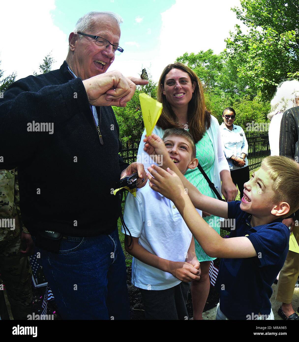 Jake and Chase Sullivan laugh at their grandfather while he jokes about the  monarch butterfly perched on his finger during Fort Lee's Butterfly Release  for fallen service members May 25 at the