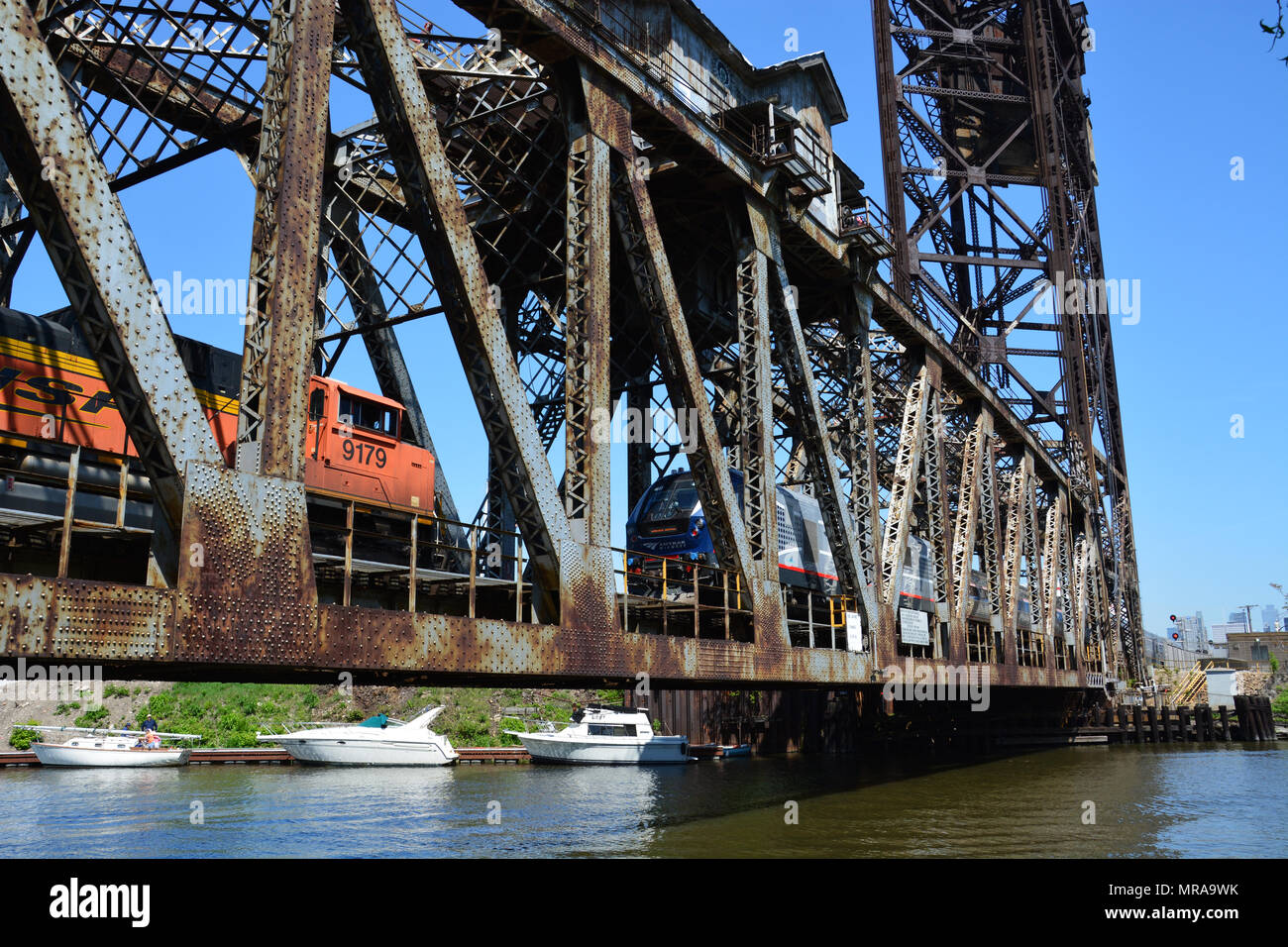 An Amtrack passenger train and BNSF freight train cross the Chicago River on the Canal Street railroad lift bridge on Chicago's south side. Stock Photo