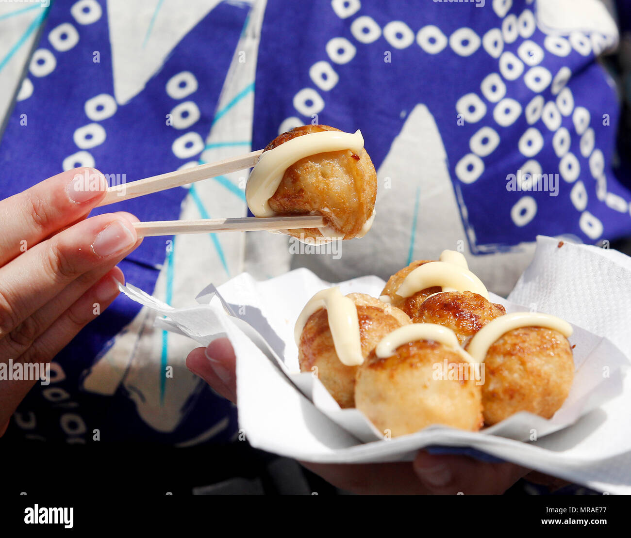 Duesseldorf, Germany, 26 May 2018, A Japanese woman eats fresh takoyaki, savory octopus balls, at the 17th Japan Day festivities. With its 7000 members, Duesseldorf's Japanese community is the third largest in Europe. Photo: Roland Weihrauch/dpa Stock Photo