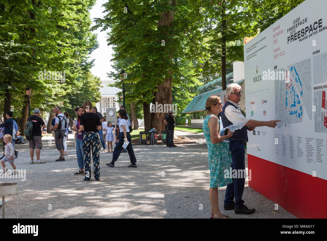 Venice, Veneto, Italy. 26th May 2018. The opening day of the 2018 Architecture  Biennale entitled Freespace in Giardini Pubblici (Public Gardens) Castello. Peopl viewing the information board with the Venice bennale Pavillion visible at the end of the tree-lined avenue. Credit MLCpicsAlamy Live News Stock Photo