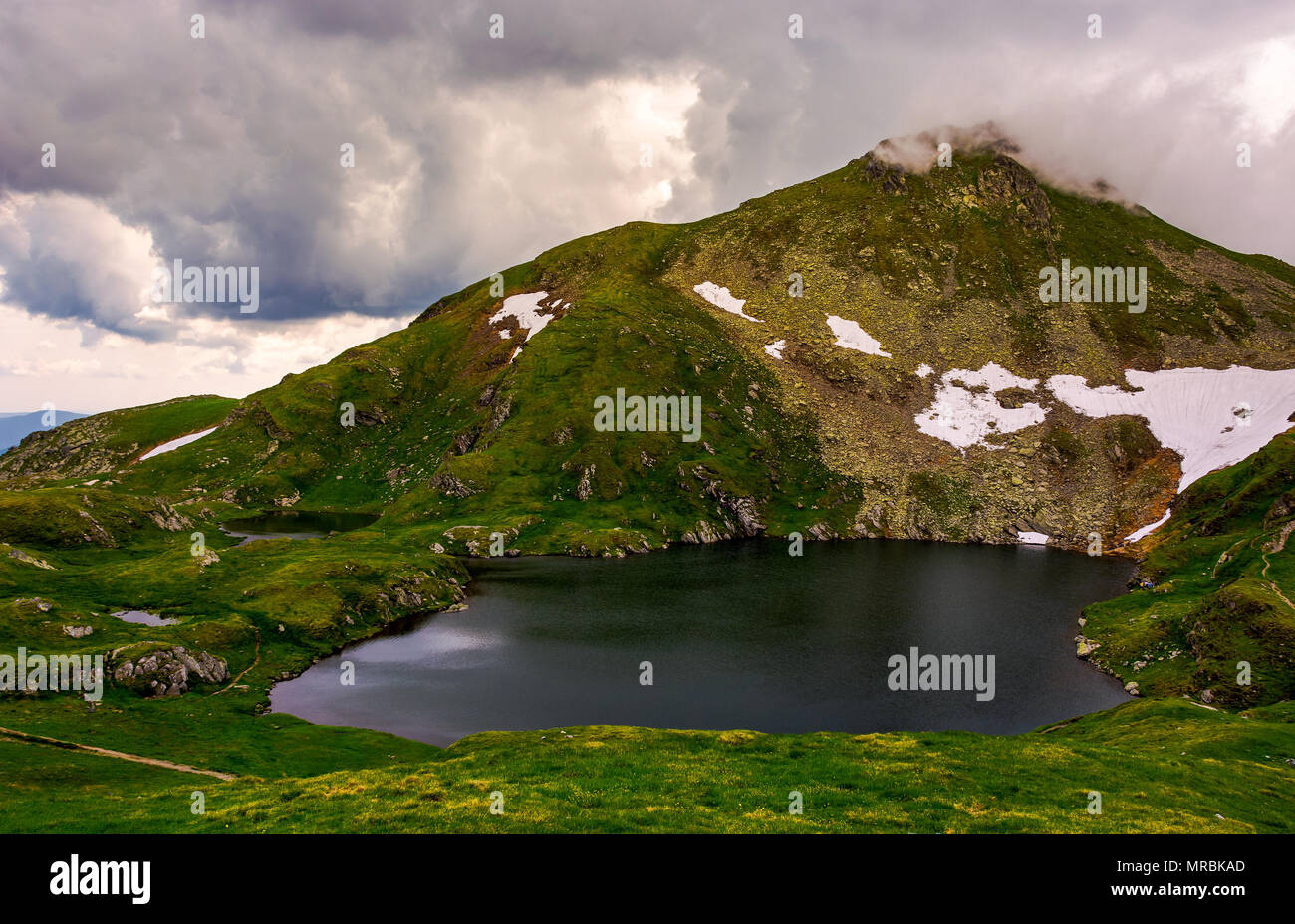 glacier lake Capra at the foot of the mountain. lovely summer scenery on a cloudy day. popular travel destination in Southern Carpathian mountains of  Stock Photo