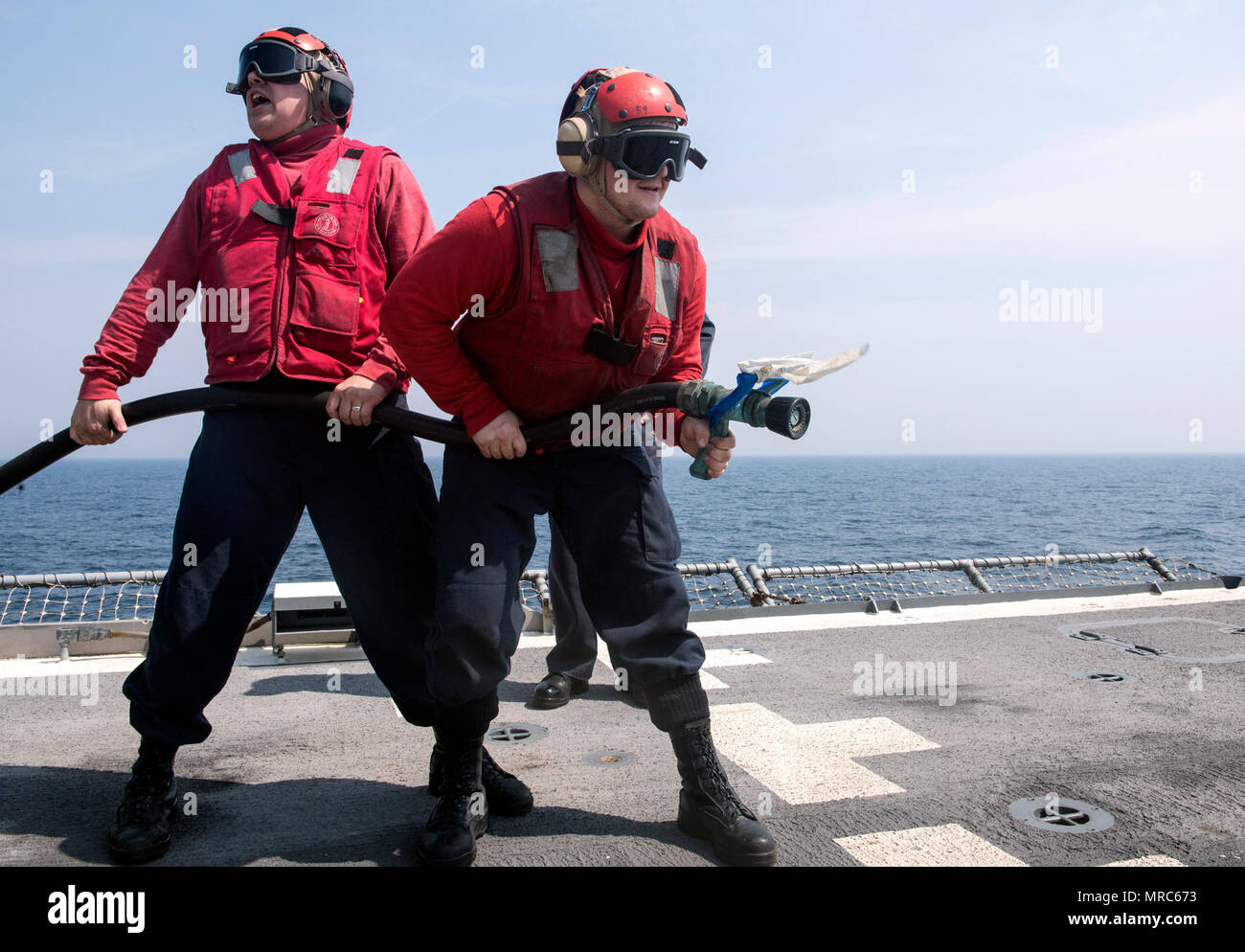 170530-N-FT178-024 WESTERN PACIFIC (May 30, 2017) Damage Controlman 1st Class Randall Miller, from Aguanga, Calif., left, and Hull Maintenance Technician 3rd Class Wane Debatin, from Pocahontas, Ill., man a fire hose during a crash and salvage drill on the flight deck of Ticonderoga-class guided-missile cruiser USS Lake Champlain (CG 57). The U.S. Navy has patrolled the Indo-Asia-Pacific routinely for more than 70 years promoting regional peace and security. (U.S. Navy photo by Mass Communication Specialist 2nd Class Nathan K. Serpico/Released) Stock Photo