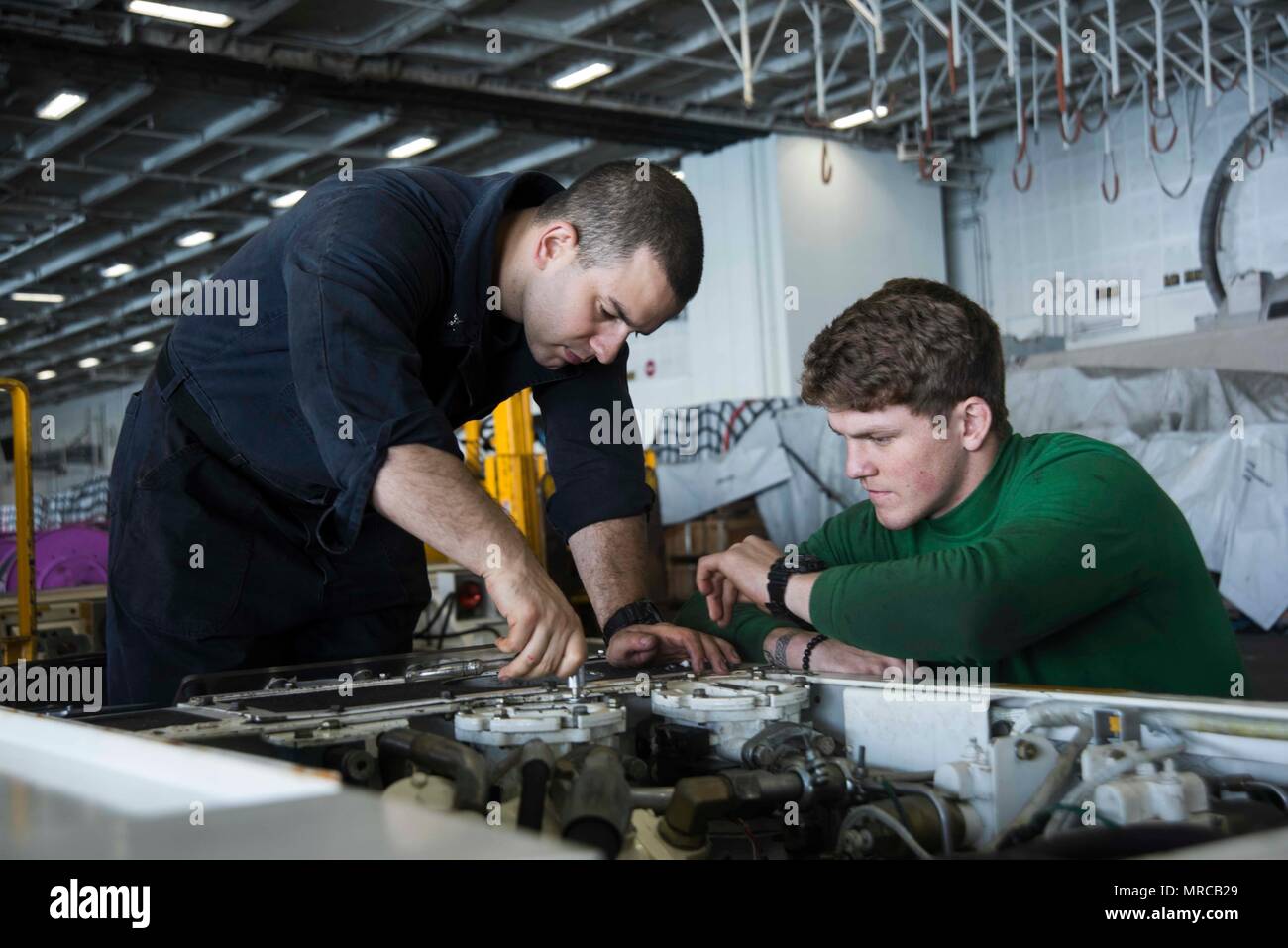 170604-N-KJ380-028  ATLANTIC OCEAN (June 4, 2017) Aviation Support Equipment Technician 3rd Class Ryan Rios, left, from Fresno, Calif., and Aviation Support Equipment Technician Airman Zane Bradbury, from Charlestown, W.Va., perform maintenance on a spotting dolly in the hangar bay of the aircraft carrier USS Dwight D. Eisenhower (CVN 69) (Ike). Ike is currently conducting aircraft carrier qualifications during the sustainment phase of the Optimized Fleet Response Plan (OFRP). (U.S. Navy photo by Mass Communication Specialist Seaman Neo B. Greene III) Stock Photo